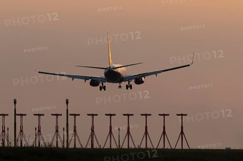 Boeing 737 jet passenger aircraft of Ryanair airlines landing over runway lights at sunset, London Stansted airport, Essex, England, United Kingdom