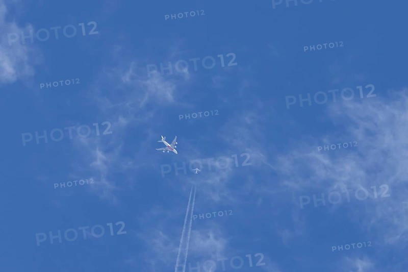 Two airliners Airbus A380 jet passenger aircraft of Emirates airlines and a Boeing 737 of Norweign Air flying in a blue sky, England, United Kingdom