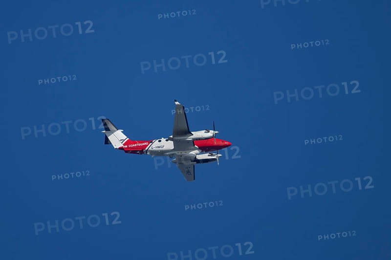 Beech King Air 350 light aircraft of the UK HM Coastguard flying in a blue sky, England, United Kingdom