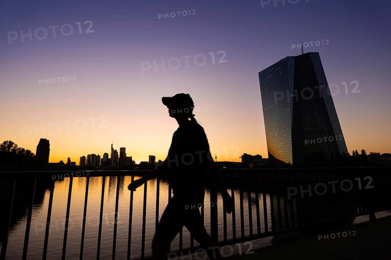 The sun sets behind the European Central Bank (ECB) and the Frankfurt banking skyline, Frankfurt am Main, Hesse, Germany