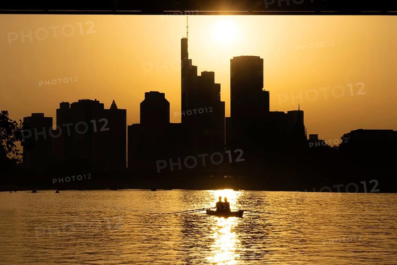 The evening sun stands over the Frankfurt banking skyline while paddlers and rowers navigate the Main, Frankfurt am Main, Hesse, Germany