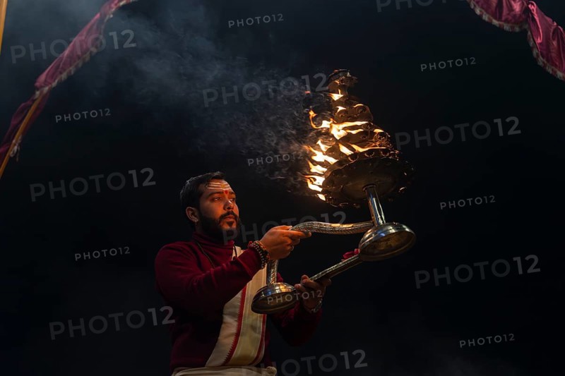 Hindu priest performing the Aarti ritual, holding a burning oil lamp, at the Ganges, Bangali Tola, Varanasi, Uttar Pradesh, India