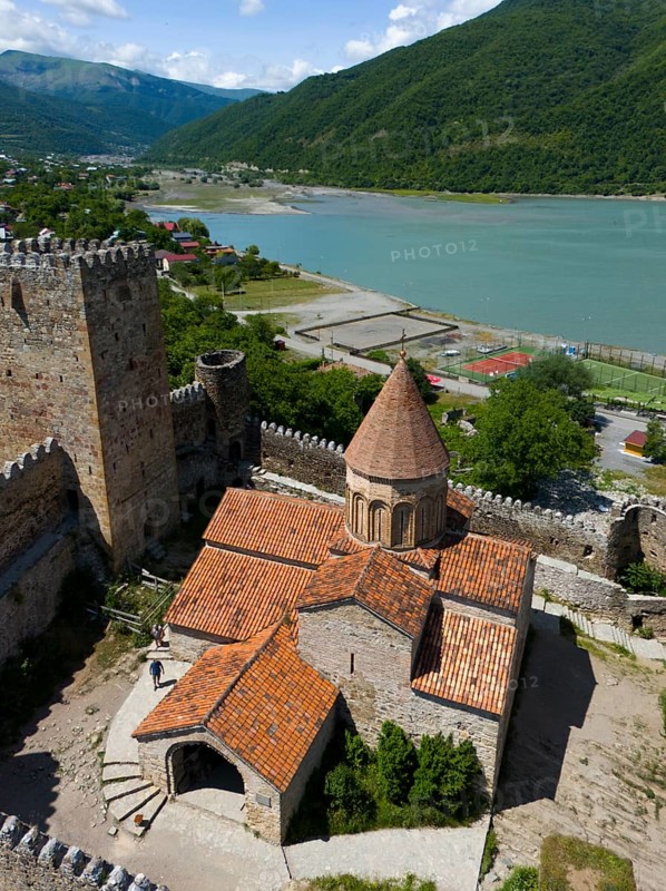 Red tiled roof of a medieval fortress church with castle walls and green lake panorama, aerial view, Ananuri Castle, Zhinvali reservoir, Shinvali, Jinvali or Shinvali, Mtskheta-Mtianeti region, Georgian Military Road, Georgia