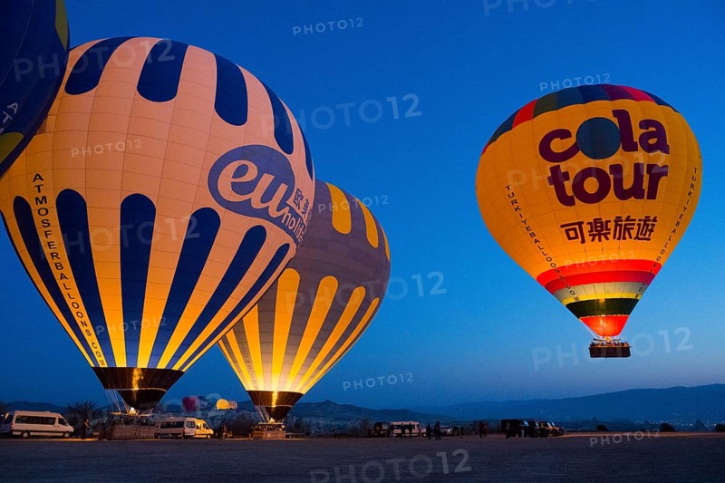 Glowing hot air balloons against a deep blue morning sky create a peaceful atmosphere on a plateau, Göreme National Park, Göreme Tarihî Millî Parki, Nevsehir Province, Nevsehir, Cappadocia, Cappadocia, Cappadocia, Cappadocia, Central Anatolia, Turkey