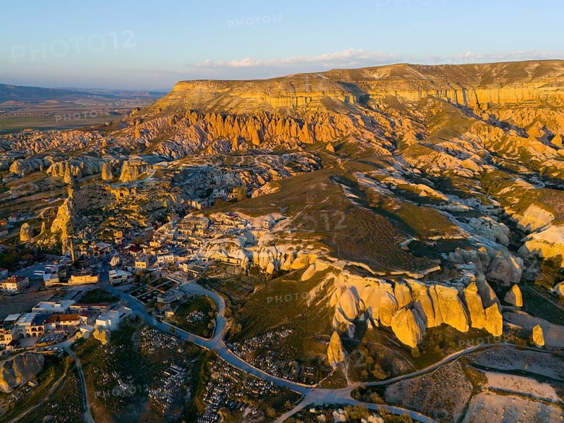 A picturesque landscape with rock formations and a small village in warm sunset light, aerial view, Göreme National Park, Göreme Tarihî Millî Parki, Nevsehir Province, Nevsehir, Cappadocia, Cappadocia, Kapadokya, Cappadocia, Central Anatolia, Turkey