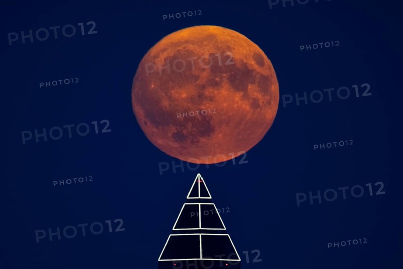 The full moon passes over the top of the Messeturm in Frankfurt am Main, Frankfurt am Main, Hesse, Germany