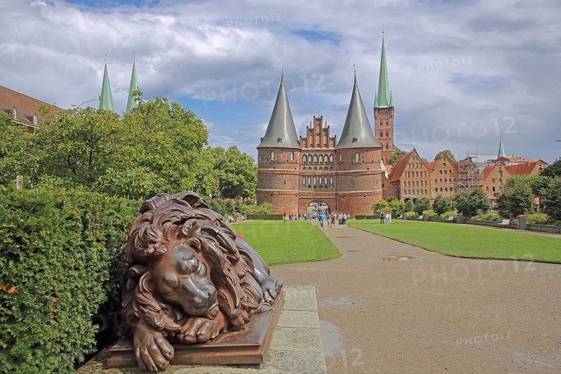 Sleeping lion figure at the historic Holstentor and St. Peter's church tower in Lübeck, Brick Gothic, Brick building, City gate, Landmark, Holstentorplatz, Old town, Lübeck, Schleswig-Holstein, Germany