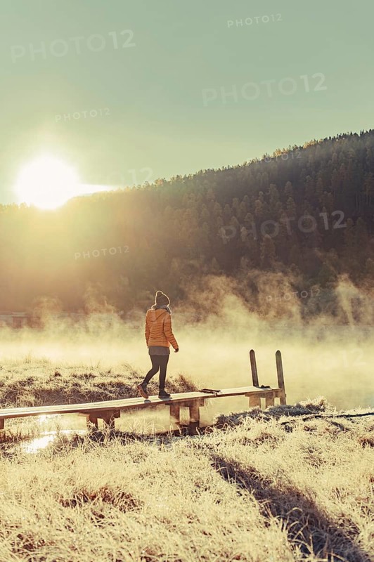 Young woman at Lake Staz near Sankt Moritz in the Engadine in Switzerland. Morning atmosphere with fog in autumn. Reflection of water