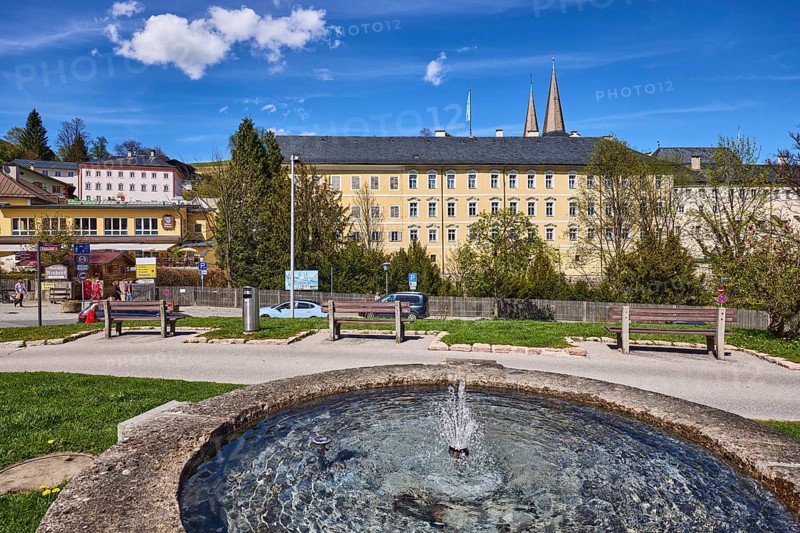 Royal Castle Berchtesgaden, Fischerbrunnen, master stonemason August Wolf, fountain, fountain made of stone, general architecture, trees, lawn, parking strip with vehicles, wooden fence, lantern, benches, blue sky, cumulus clouds, cirrostratus clouds, Am Fischerbichl, Bahnhofstraße, Berchtesgaden, Upper Bavaria, district Berchtesgadener Land, Bavaria, Germany