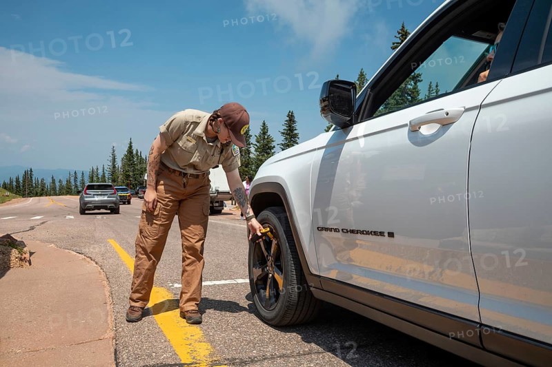 Colorado Springs, Colorado - A Pikes Peak ranger checks the temperature of brakes on a car descending 14, 115' Pikes Peak. If the brakes have become hotter than 300 degrees F, travelers must stop to let the brakes cool before continuing their descent