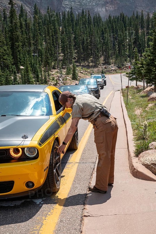 Colorado Springs, Colorado - A Pikes Peak ranger checks the temperature of brakes on a car descending 14, 115' Pikes Peak. If the brakes have become hotter than 300 degrees F, travelers must stop to let the brakes cool before continuing their descent