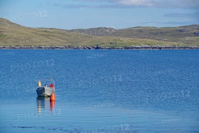 Lonely boat next to buoy on calm water, hilly landscape behind under clear sky, Hillswick, Eshaness, Shetland Islands, Scotland, United Kingdom