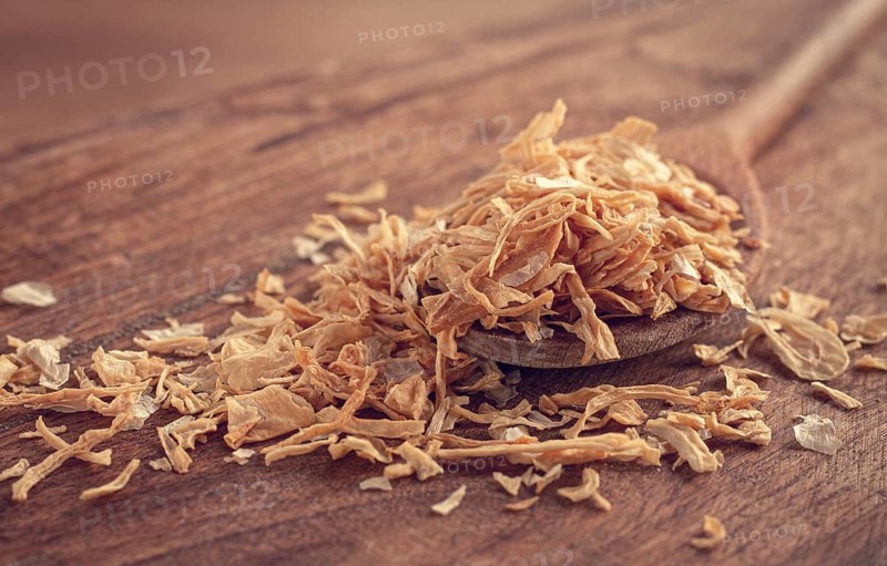 Smoked onion flakes, on a wooden spoon, wooden table, close-up