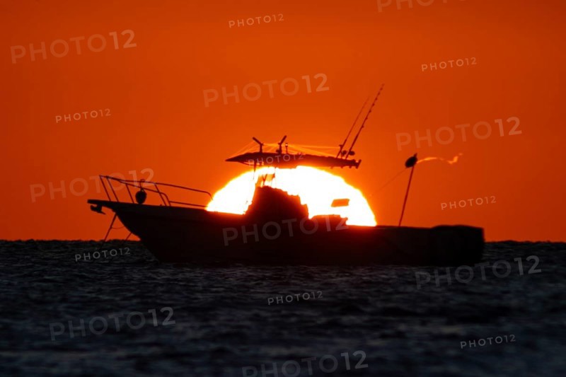 The sun rises behind a boat on the Costa Rei, a coastal stretch of the Italian Mediterranean island of Sardinia, Monte Nai, Costa Rei, Sardinia, Italy