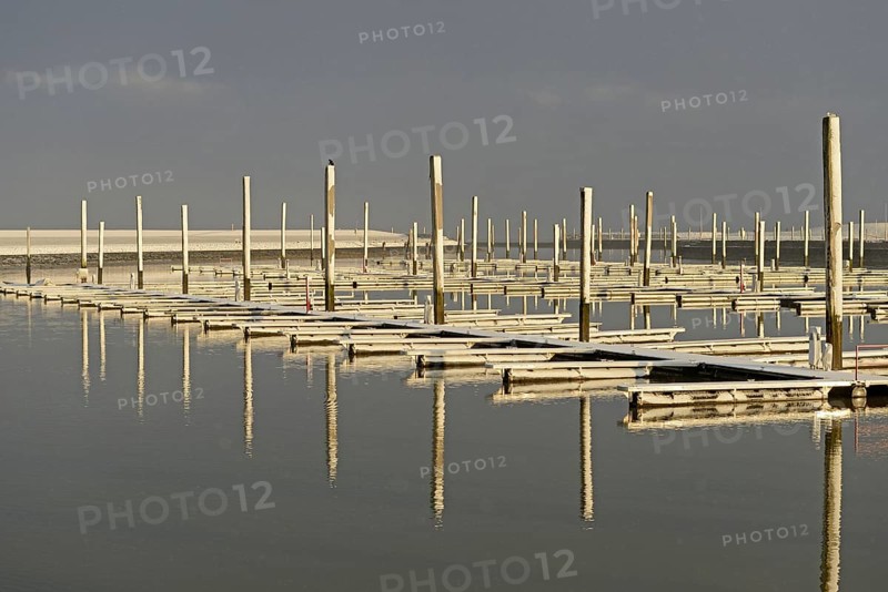Winter day, onset of winter, morning sun shining on the snow-covered jetties in the marina, North Sea, Norddeich, Lower Saxony, Germany