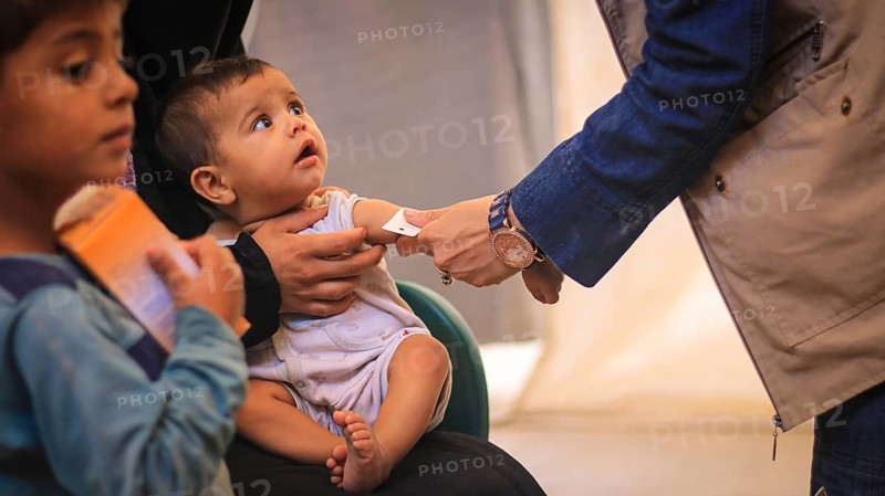 A doctor examines children's malnutrition inside a refugee camp