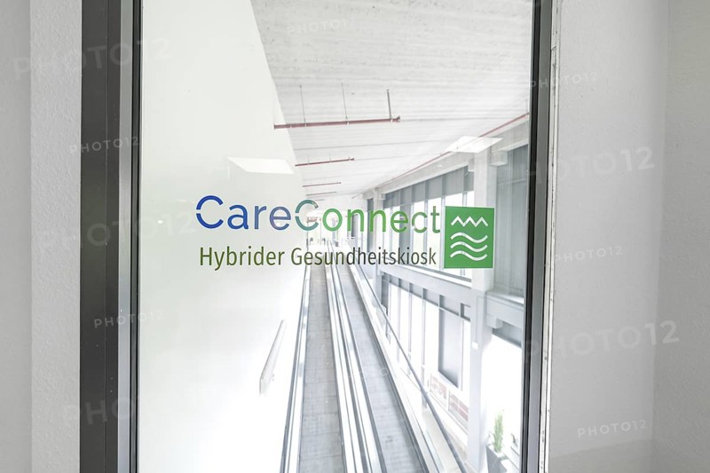 Bright escalator with CareConnect logo in a modern building, Care Connect, vaccination kiosk for refugees, Calw, Germany