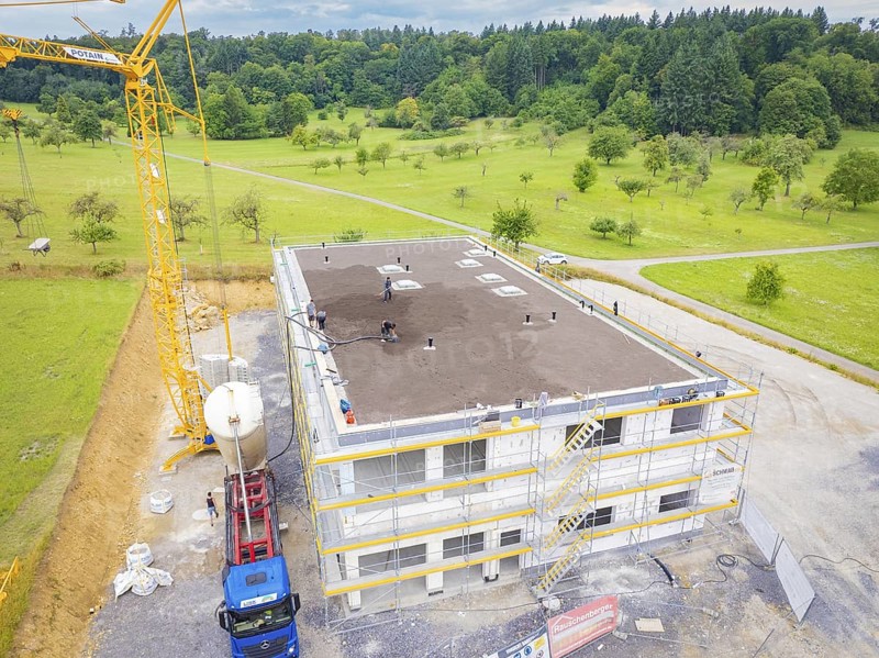 Construction site with a building under construction and a crane on a field, green roof, house construction, climate neutral