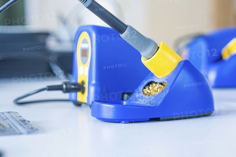 Blue soldering iron on a table with yellow accents and digital display