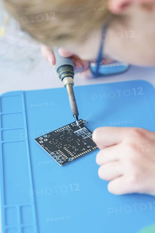 Person soldering on a circuit board lying on a blue base