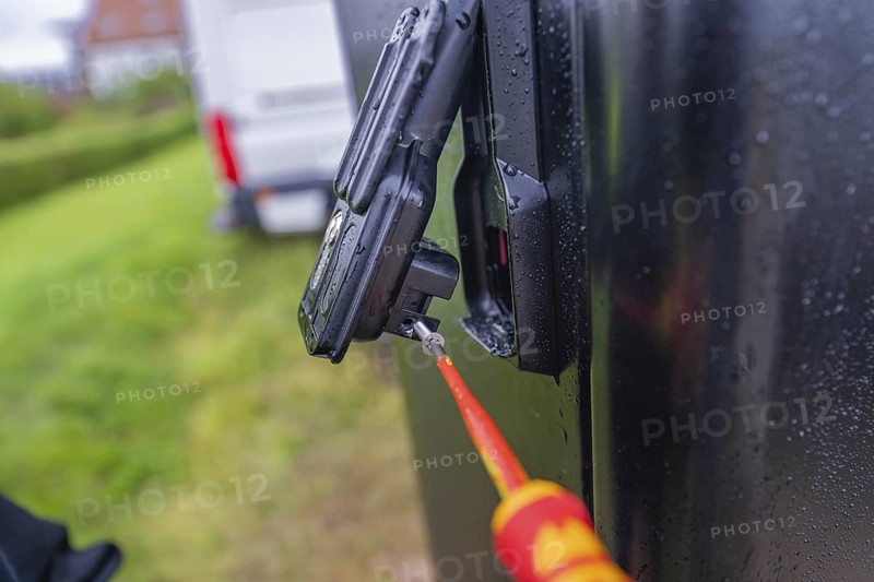 Screwdriver in use on a wet, black housing outdoors, assembly of a charging station for electric cars, Calw, Germany