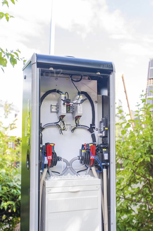An open outdoor power box in front of a blue sky and green bushes, installation of a charging station for electric cars, Calw, Germany