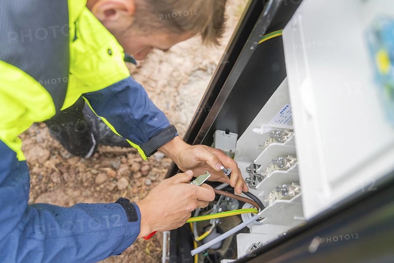 A person uses a tool to carry out work on an electrical switch box, assembly of a charging station for electric cars, Calw, Germany