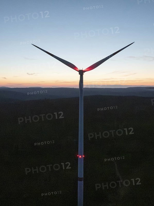 Wind turbine in front of a colourful sunset on the horizon. The sky glows in blue, red and orange, Simmersfeld, Black Forest, Germany