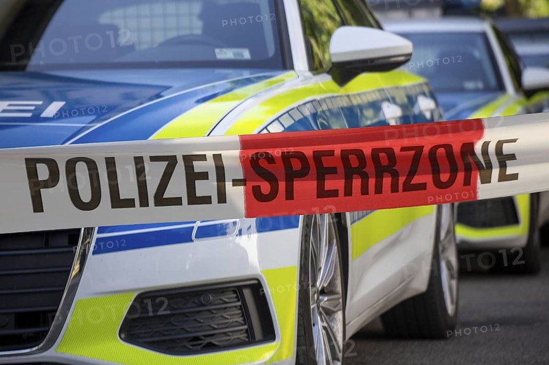 (Photomontage) Symbolic image of a police operation: police cordon in front of emergency vehicles