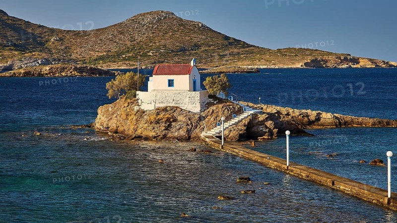 Whitewashed chapel on island, accessible via footbridge, surrounded by calm blue water, chapel, church, Agios Isidoros, rocky islet, Bay of Gourna, Kokkali, Leros, Dodecanese, Greek Islands, Greece