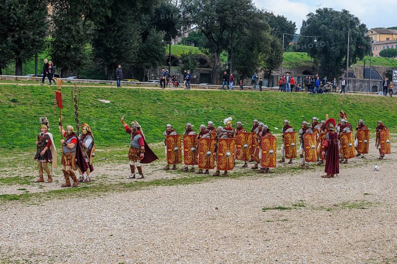 Traditional group Roman legionaries soldiers in line up with large shield and swords next to Centurion Centurion in front of coat of arms bearer of standard, Circus Maximus, Rome, Italy