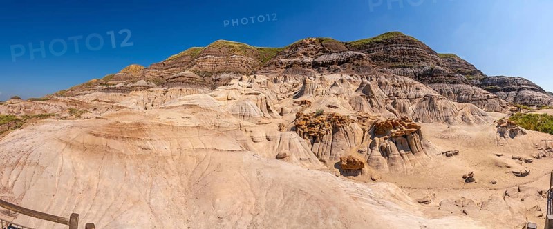 Breathtaking panorama of the drumheller badlands showcasing unique hoodoo formations under a vibrant blue sky, highlighting the geological wonders of the canadian prairies