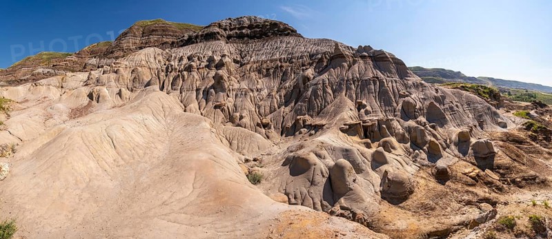 Panoramic view of unique hoodoo rock formations in drumheller, alberta, showcasing the geological wonders of the canadian badlands under a clear blue sky