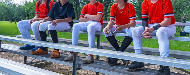 Young baseball players sitting together on bleachers, enjoying camaraderie and conversation after a challenging game, showcasing teamwork and sportsmanship