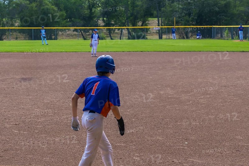 Young baseball player is walking on the infield during a game, wearing a blue and orange jersey with the number one, white pants, a blue helmet, and batting gloves