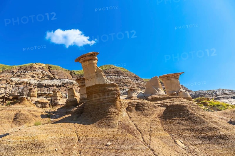 Breathtaking hoodoo rock formations dominate the arid landscape of drumheller, canada, under a vibrant blue sky, creating a dramatic and otherworldly scene