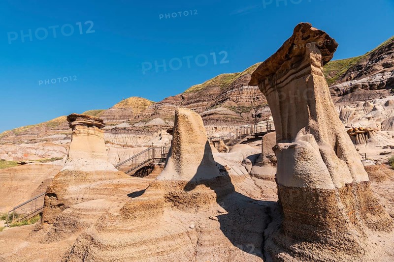 Breathtaking view of unique sandstone formations, known as hoodoos, dominating the landscape of drumheller valley in the canadian badlands under a vibrant blue sky
