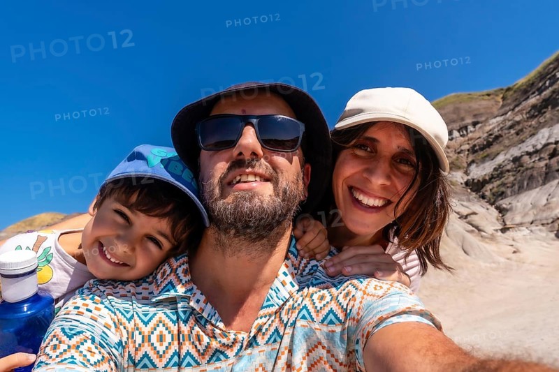 Happy family with a small child taking a selfie portrait with the arid landscape of drumheller, alberta, canada, in the background on a sunny summer day