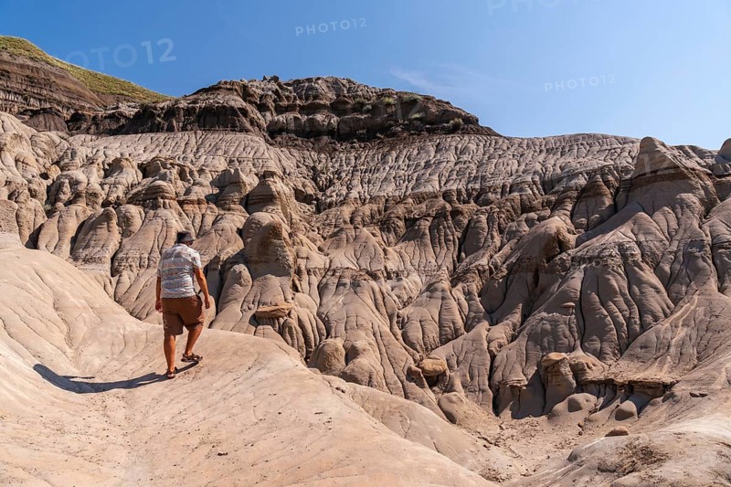 Tourist walking in horseshoe canyon near drumheller, alberta, under the summer sun, exploring the arid and eroded landscape of the canadian badlands