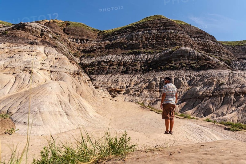 Tourist admiring the landscape of horseshoe canyon in drumheller, alberta, canada, enjoying the beautiful arid landscape under blue sky on a sunny summer day