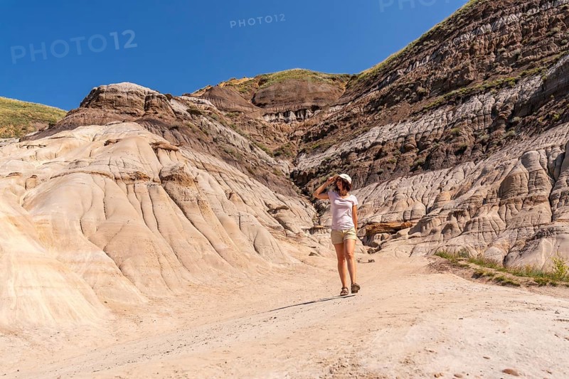 Female tourist walking through the arid and eroded landscape of drumheller valley in the canadian badlands, enjoying the sunny summer day and breathtaking geological formations