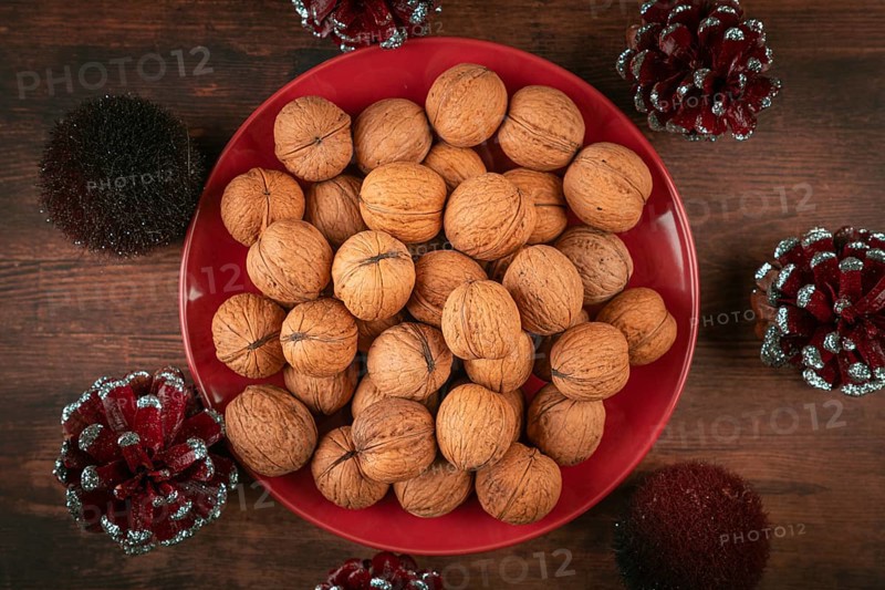 Red plate with walnuts surrounded by sparkling cones
