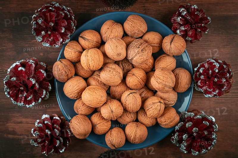 Blue plate full of walnuts surrounded by decorative cones
