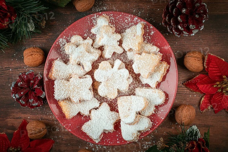 Christmas cookies with powdered sugar surrounded by decoration and walnuts