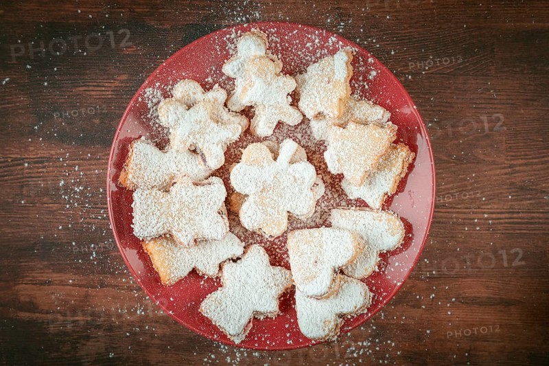 Christmas cookies with powdered sugar on red plate