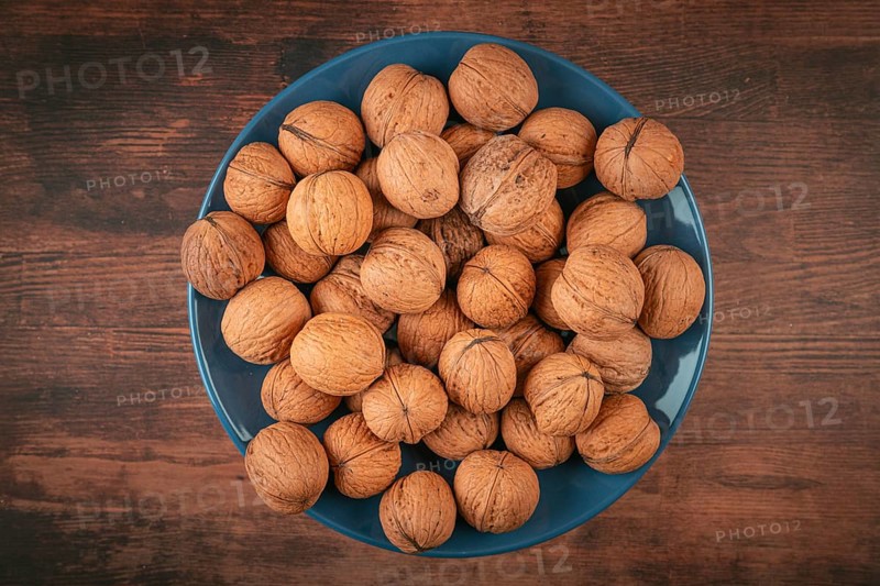 Blue plate with walnuts in the center of a wooden table