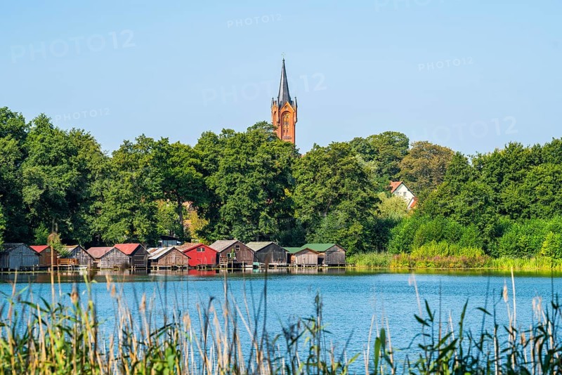 View across the Haussee to the town church and colorful boathouses on stilts, Feldberg, Feldberg Lake District, Mecklenburg-Western Pomerania, Germany
