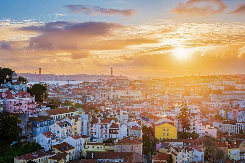 View of Lisbon famous view from Miradouro da Senhora do Monte tourist viewpoint of Carmo Convent Ruins and 25th of April Bridge on sunset. Lisbon, Portugal