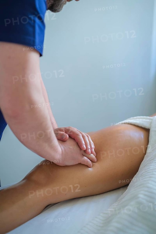 A skilled therapist performs a soothing leg and thigh massage using oil, promoting relaxation and wellness in a tranquil spa setting