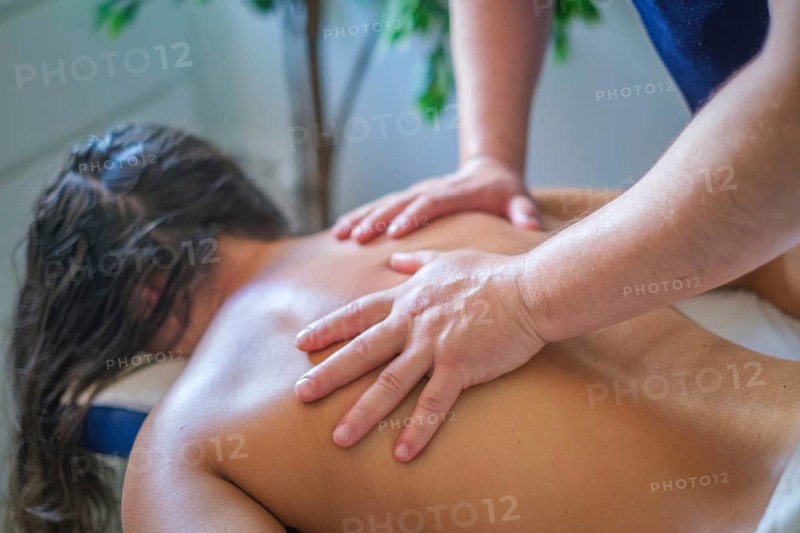 A woman enjoys a professional back massage in a soothing spa environment, focusing on relaxation and lymphatic drainage with oil